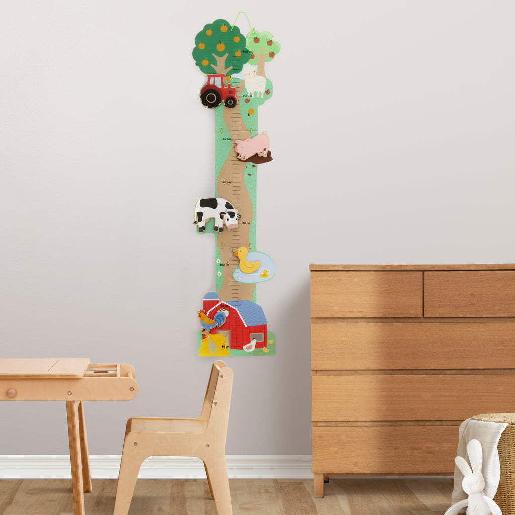 Houten groeimeter met boerderijthema gemonteerd aan de muur in een kinderkamer.