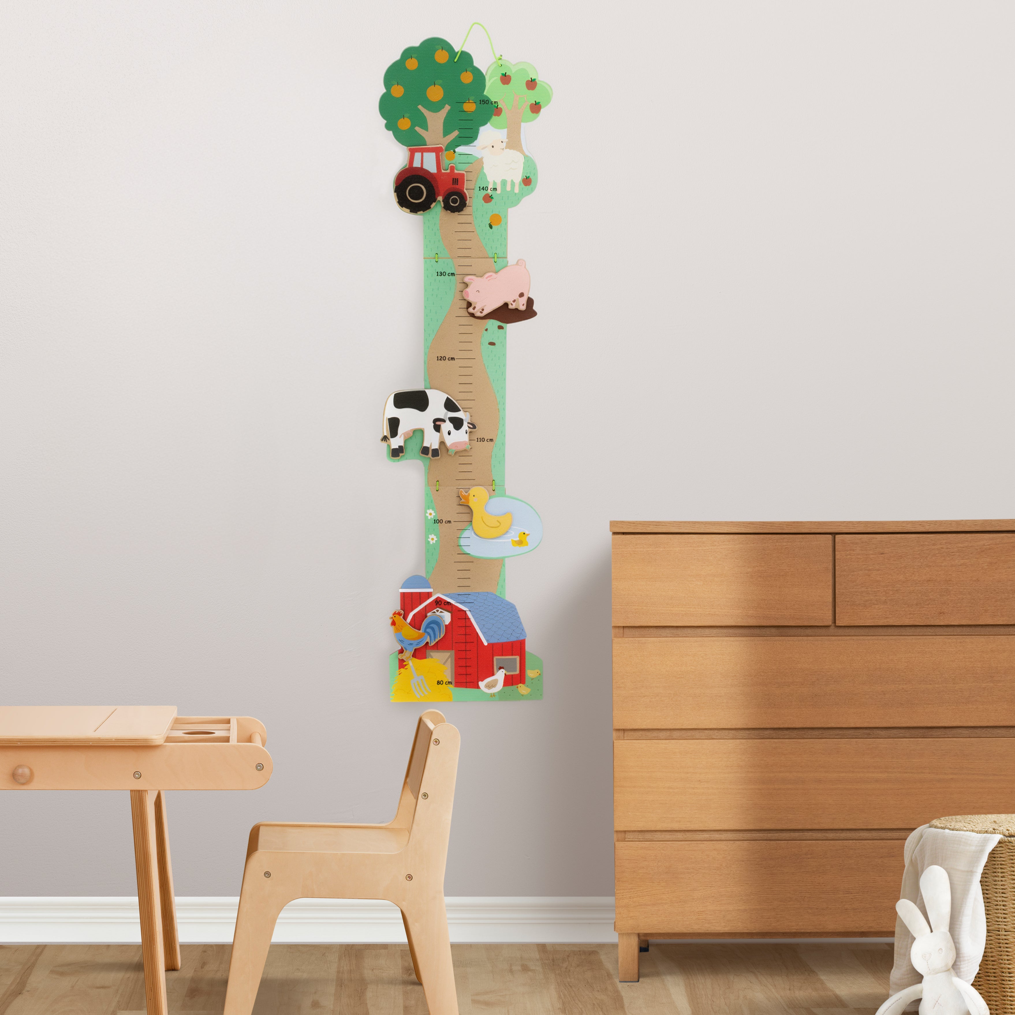 Houten groeimeter met boerderijthema gemonteerd aan de muur in een kinderkamer.
