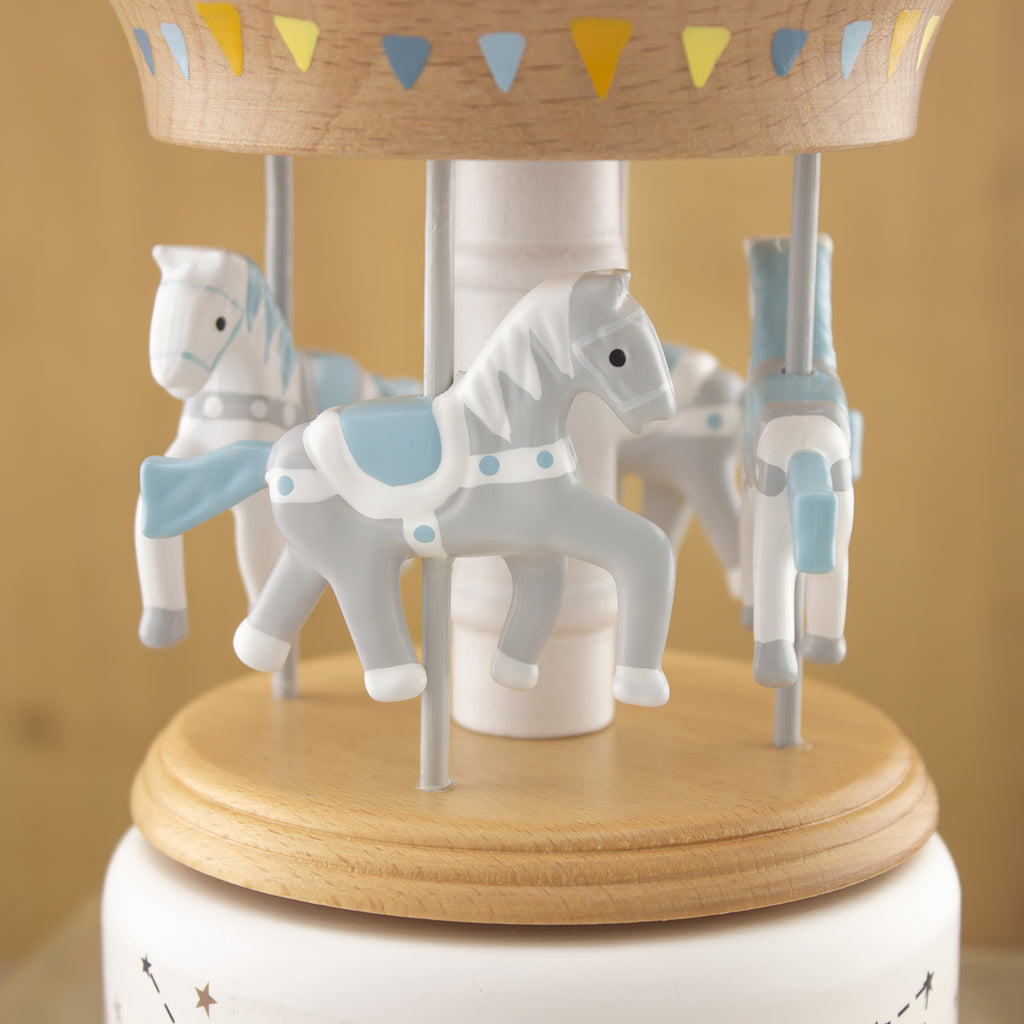 Detail van houten muziekcarrousel met witte en lichtblauwe paarden op metalen stangen.