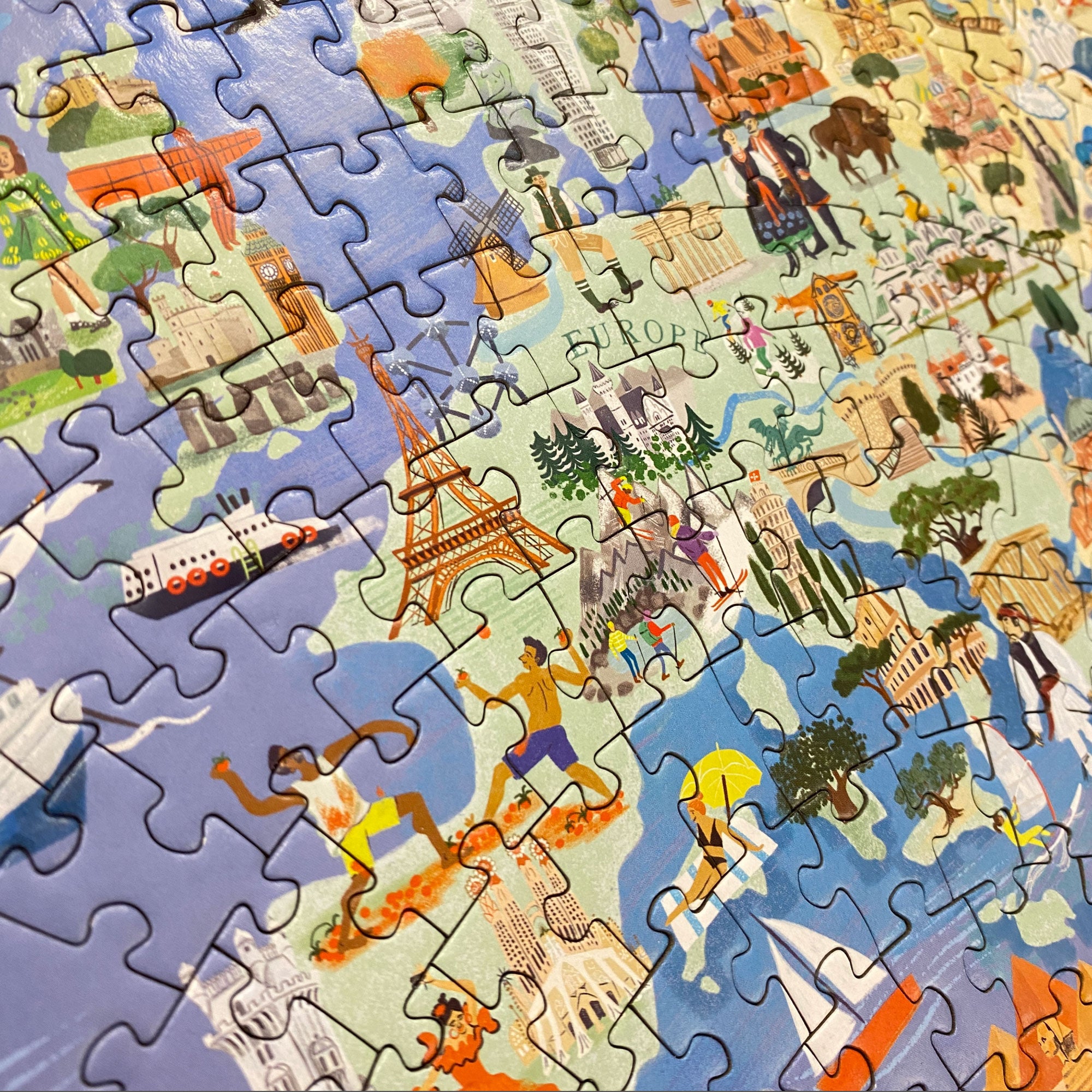 Close-up van puzzelstukjes van een wereldkaart met iconische gebouwen en landschappen
