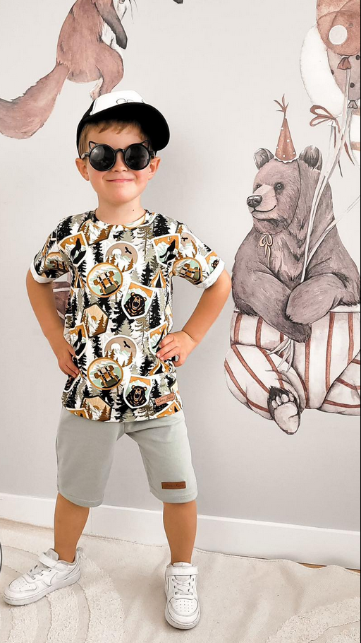 Jongen draagt een T-shirt met bos print en een groene short.