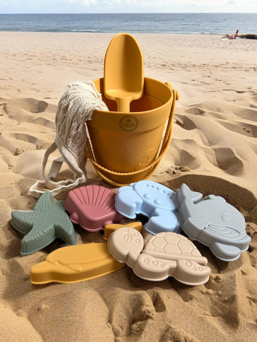 Siliconen strandspeelgoed set met emmer, schep en zeevormpjes op het strand, flexibel en kindvriendelijk speelgoed voor zand en water.