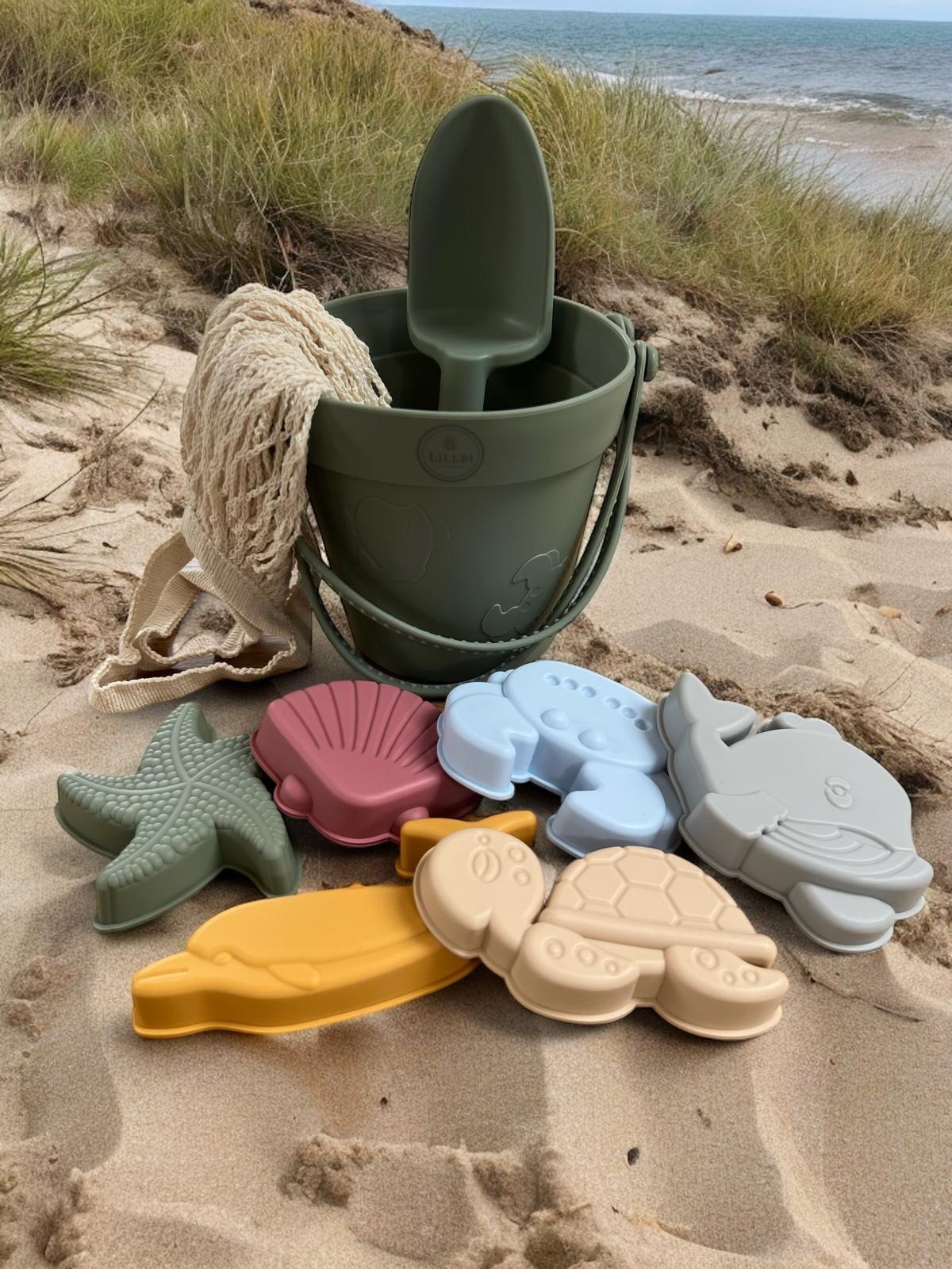 Groene siliconen strandspeelgoed set met emmer, schep en zeevormpjes op het strand, flexibel speelgoed voor zand en water.