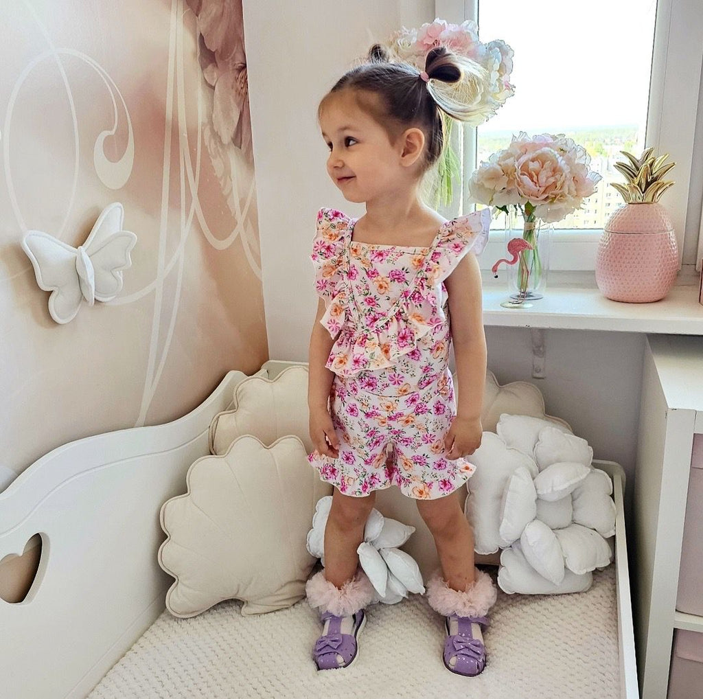 Meisjes zomerse T-shirt met bloemenprint en ruches, gedragen door een kind in een lichte kinderkamer.