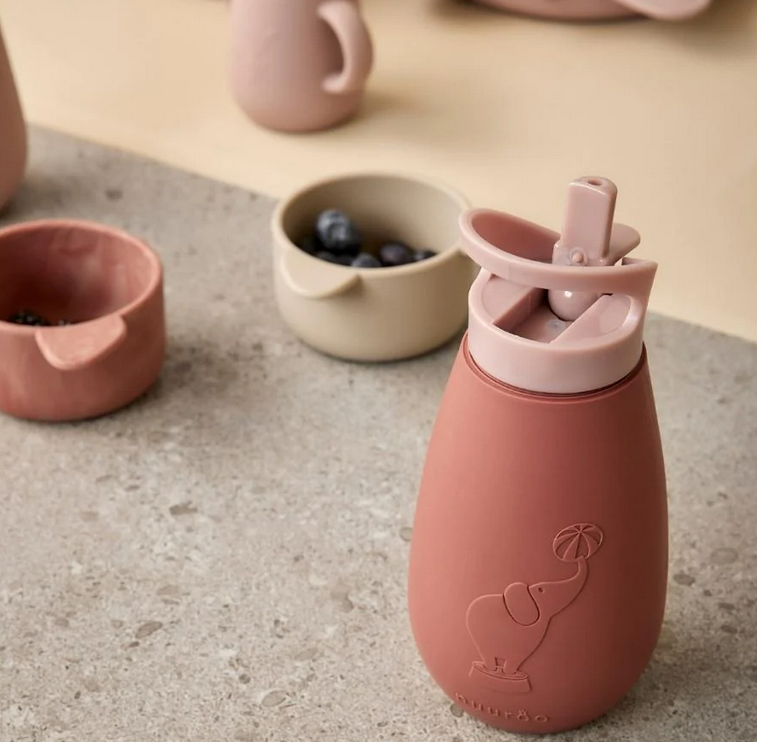 Roze baby drinkfles met rietje en handvat op keukenblad