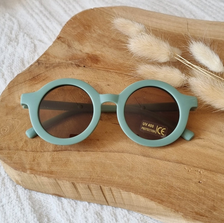 Saliegroene ronde kinderzonnebril met UV400-bescherming op houten ondergrond